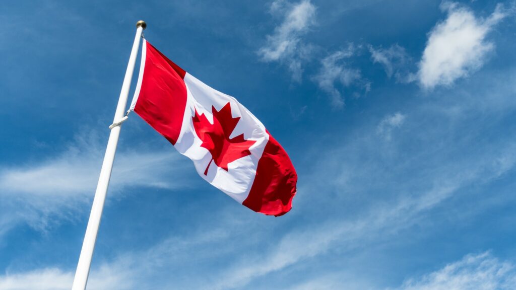 Canadian flag flying with a blue sky.
