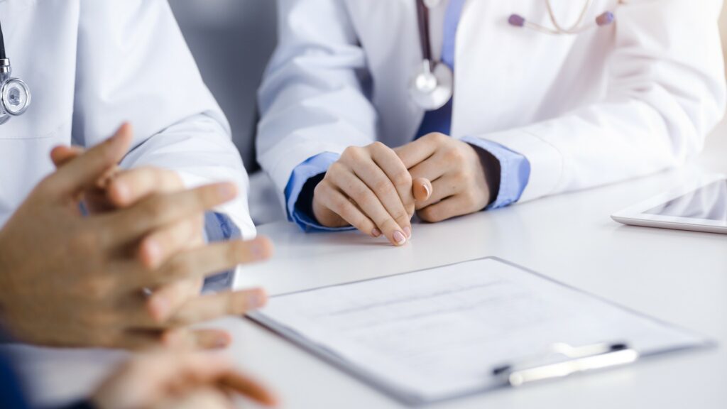 Two doctors looking at paperwork on clipboard.