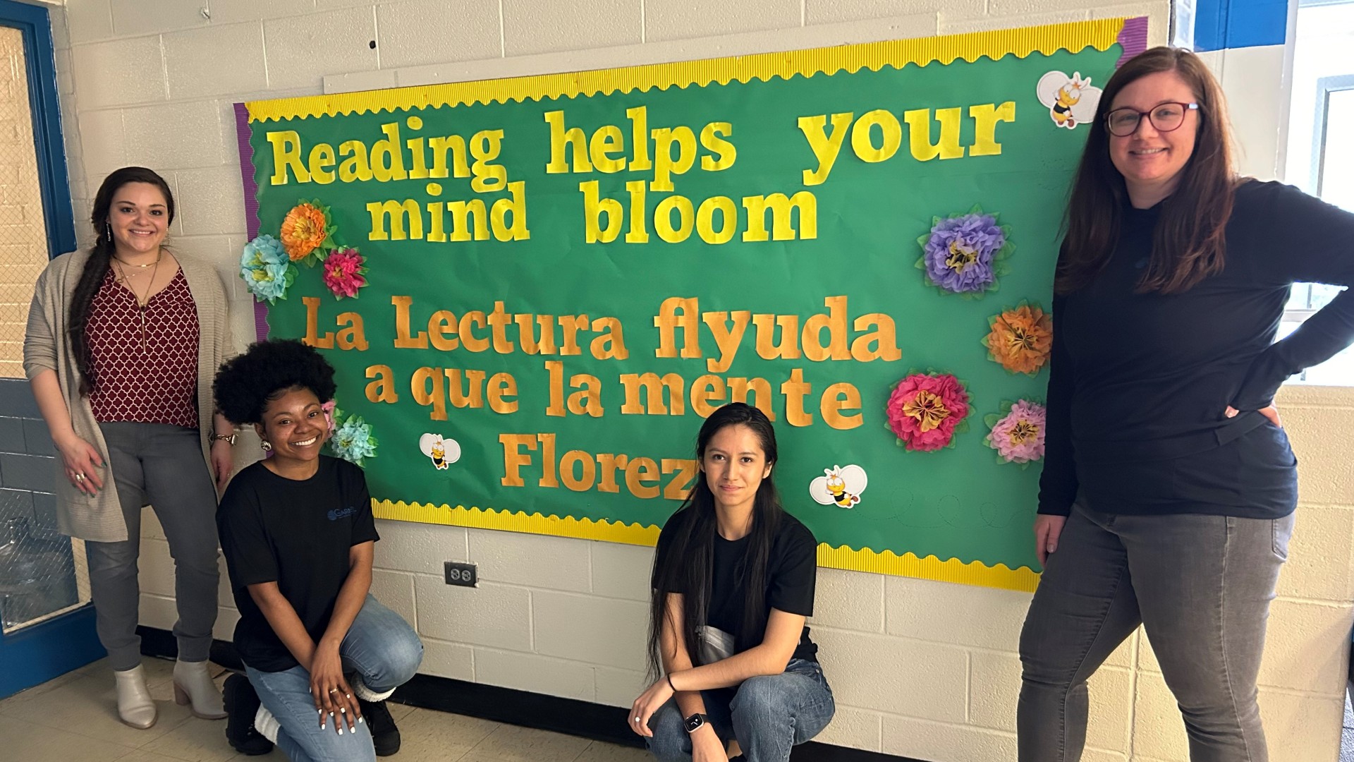 Members of Garfinkel Immigration Law Firm next to a bulletin board they decorated at the Charlotte Bilingual Preschool. 